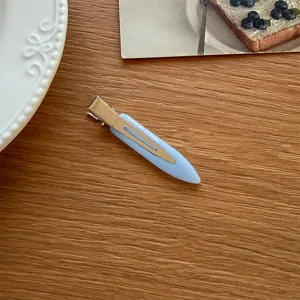 Nahaufnahme der minimalistischen hellblauen Entenschnabel-Haarspange auf Holz, feines Detail.