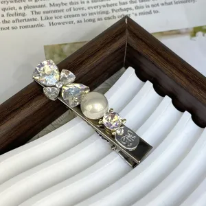 Close-up detail of a silver hair clip decorated with sparkling crystals and a white pearl.