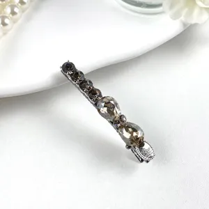 Crystal hairpin detail view featuring sparkling dark rhinestones on a sleek metal barrette base.