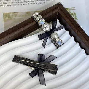 Close-up view of elegant black bow hair clip featuring sparkling rhinestones and pearls.