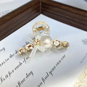 Small hair claw clip with clear resin, sparkling rhinestones, faux pearl, and cute bow.