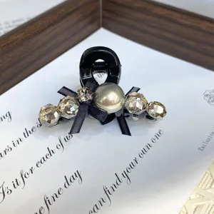 Detailed close-up of mini black hair claw clip featuring sparkling rhinestones and pearl.