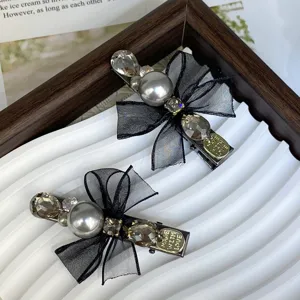 Close-up detail of the elegant black mesh bow hair clips featuring shiny rhinestones and pearls.