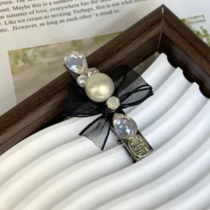 Close-up detail of elegant black mesh bow hair clip featuring shiny rhinestones and pearls.