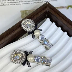 Detailed close-up of silver hair clip featuring sparkling crystals, pearls, and a black bow.