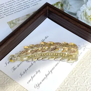Close-up of elegant crystal leaf banana hair clip, sparkling rhinestones on golden frame detail.
