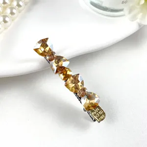 Close-up view of the elegant rhinestone crystal duckbill hair clip with sparkling amber stones.