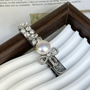 Silver hair clip with pearls and rhinestones, elegant bow design for side hair styling.
