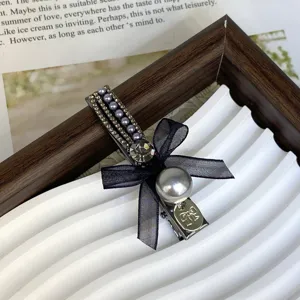Exquisite rhinestone pearl hair clip with black bow detail, elegant side hairpin for women style.