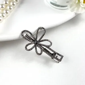 Close-up detail shot of a sparkling rhinestone hairpin on white background with pearl props.