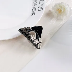 Pince à cheveux triangulaire noire avec détails de fleurs et strass délicats pour un coiffage chic.