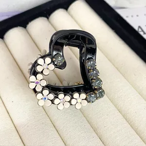 Elegant black heart hair claw clip with white flowers and sparkly rhinestones for charming styling.