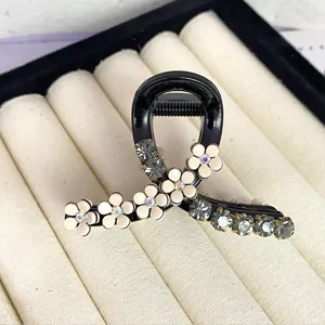 Detailed shot of sparkling rhinestone camellia hair claw, elegant black hair accessory design.