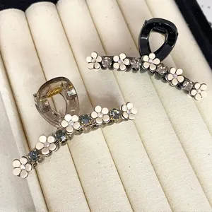 Close-up of elegant camellia hair claws with sparkling rhinestones on display tray.