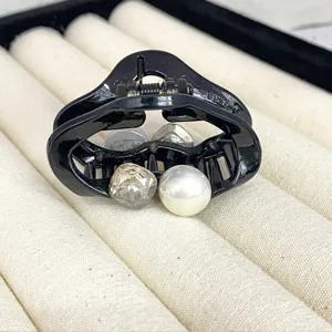 Black hair claw clip for women, small styling accessory with pearl and crystal details.