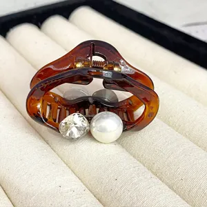 Tortoise shell hair claw clip featuring sparkling crystal and pearl detail for elegant hairstyles.