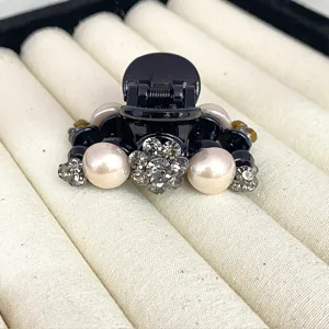 Detailed view of black rhinestone camellia hair claw clip with faux pearls for women styling.