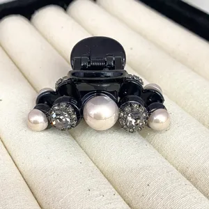 Detailed view of a chic black hair claw clip adorned with elegant pearls and sparkling rhinestones.