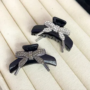 Detail view of stylish black rhinestone hair claw clips on a beige velvet jewelry tray.