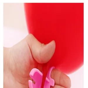 Vista detallada de un atador de globos de plástico rosa en uso, ideal para fiestas y eventos.