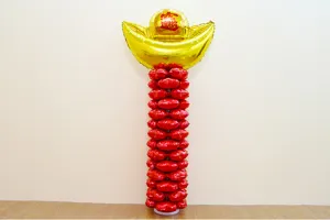 Detail shot of festive balloon column with gold ingot top and red stacked balloons for events.
