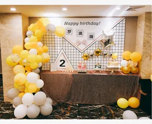 Detailed view of birthday party balloon arch setup with yellow, white and grey balloons.