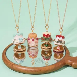 Gros plan des détails de colliers pendentifs gâteau émaillé exquis sur un miroir en bois.