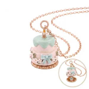 Collier pendentif médaillon gâteau émaillé avec chaîne dorée, nœud et décor floral.