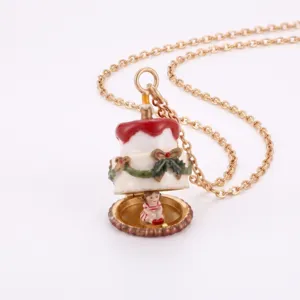 Collier pendentif ouvrant gâteau de Noël avec chaîne dorée, nœud de baies et bougie cadeau.