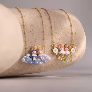 Close-up detail of fairy tale doll necklace featuring cute resin figurines on stone prop.