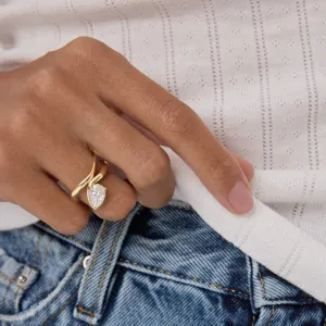 Detailopname van een stijlvolle geometrische goudkleurige ring met sprankelende peersteen.