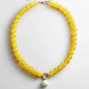 Gedetailleerde close-up van de gele kralenketting met een prachtige parelhanger detail.