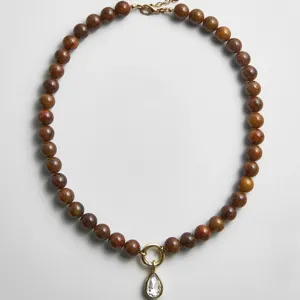 Handgemaakte kralenketting met druppelvormige kristallen hanger en bruine ronde kralen.