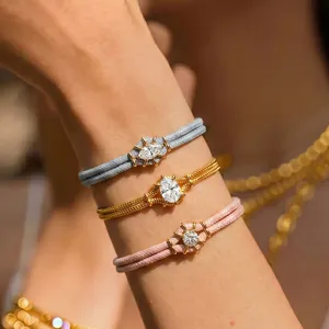 Detailopname van stapelbare macaronkleurige gevlochten armbanden met sprankelende zirkonia bedels.