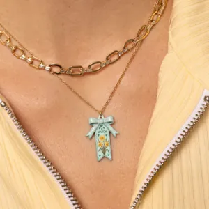 Gros plan détail du collier nœud ruban fleur de naissance de mars avec émail bleu chaîne.