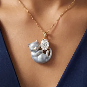 Gros plan sur le collier pendentif chat endormi argenté avec pierre zircon ovale brillante.