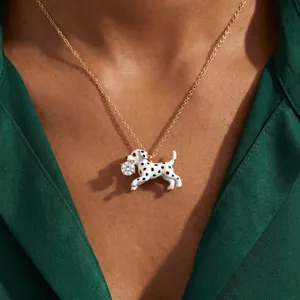 Gros plan d'un collier pendentif chien dalmatien mignon avec zircone étincelant, plaqué or.