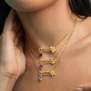 Vue détaillée de colliers épingles de sûreté plaqués or avec pendentifs et fleurs.
