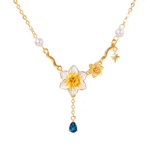 Detailopname van de vergulde decemberbloemketting met geëmailleerde narcishanger en blauwe steen.