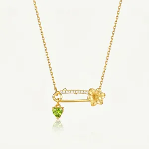 Vue détaillée du collier épingle à nourrice doré avec pierre de naissance cœur vert.