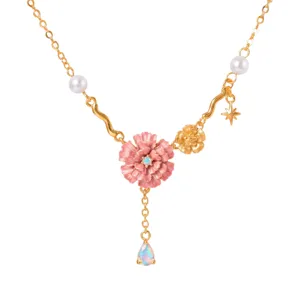 Gedetailleerde close-up van vergulde bloemhanger ketting met roze emaillering en parels.