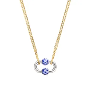 Gros plan d'un collier en chaîne dorée avec pendentif argenté et perles en porcelaine.