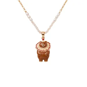 Gros plan détaillé d'un collier pendentif ours brun mignon avec perles et chaîne dorée.