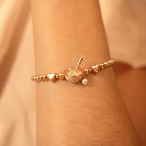 Gros plan d'un bracelet extensible en or rose sur le thème de la pâtisserie avec un bol.