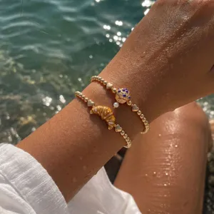 Bracelets élastiques perlés dorés avec des breloques mignonnes de croissant et cupcake.
