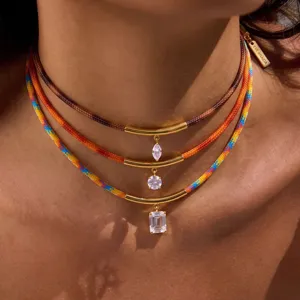 Collar superpuesto de cordón trenzado con tubos dorados curvos y colgantes de cristal geométrico