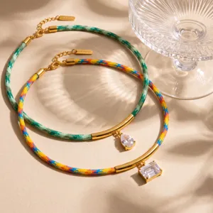 Collar de cuerda trenzada con patrón tejido colorido, tubo dorado curvo y colgante de cristal.
