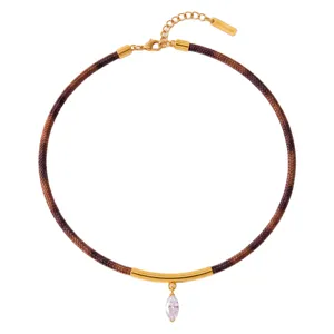 Collar chic de cordón trenzado marrón con tubo curvo dorado y colgante de cristal.