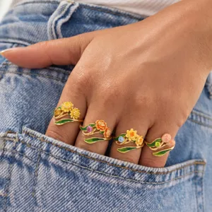 Detailed close-up of gorgeous floral enamel rings worn on fingers, charming jewelry style.
