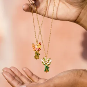 Primer plano detallado de elegantes collares ramo de flores de esmalte con cadenas doradas.